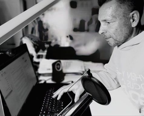Mann am Laptop mit Notizen und einer Tasse, konzentriert auf die Arbeit.